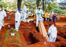 Empleados del servicio funerario entierran a una víctima de la covid-19, en el cementerio de Vila Formosa, en São Paulo (Brasil).