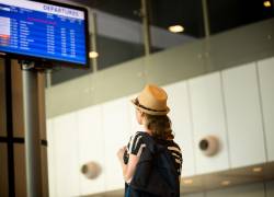 Mujer observa el panel de salidas de vuelos en un aeropuerto. (Foto: Freepik.)