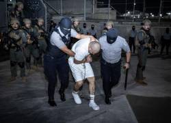 Fotografía cedida por la Presidencia de El Salvador, donde se observa a guardias del Centro de Confinamiento del Terrorismo (Cecot), trasladando a supuestos miembros de la banda criminal conocida como Tren de Aragua.