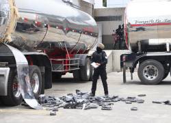 Un agente antidrogas de la Policía Nacional de Ecuador encuentra bloques de cocaína en un compartimento oculto de un camión este jueves, en Tulcán.