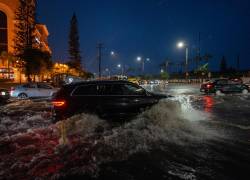 Vehículos transitan por una vía inundada debido a fuertes lluvias este martes, en el cantón Samborondón.