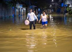 Ciudadanos caminando por una zona anegada en la ciudad de Babahoyo, provincia de Los Ríos.