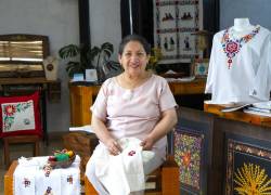 Teresa Casa Ponce, fundadora de Catelina, sentada junto a sus bordados dentro del taller donde capacita a quienes mantendrán la ancestral técnica.