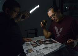 Fotografía de un hombre leyendo el periódico durante un apagón en Cuenca.