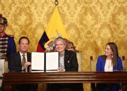 El presidente de la República, Guillermo Lasso, sostiene el documento en cuestión junto al ministro de Gobierno, Henry Cucalón.