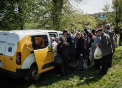 La empleada postal Iryna Fedyania distribuye las pensiones a los temerosos jubilados ucranianos que se aglutinan en torno a su furgoneta.