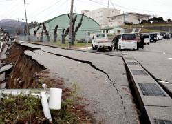 La gente se encuentra junto a grandes grietas en el pavimento después de ser evacuada a una calle en la ciudad de Wajima, prefectura de Ishikawa, el 1 de enero de 2024, después de que un gran terremoto de magnitud 7,5 sacudiera la región de Noto en la prefectura de Ishikawa por la tarde.