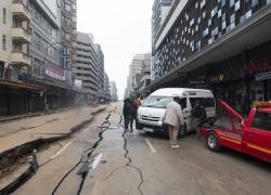 Una grúa se prepara para remolcar un vehículo dañado junto a una carretera dañada en Johannesburgo