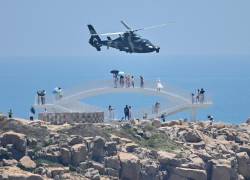 Los turistas observan cómo un helicóptero militar chino sobrevuela la isla de Pingtan, uno de los puntos más cercanos de China continental a Taiwán.