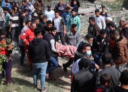 Los palestinos cargan el cuerpo de una persona muerta en un bombardeo israelí.