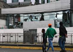 Personas caminan frente a la Contraloría destrozada cerca del edificio de la Asamblea Nacional en Quito el 26 de junio de 2022, en el marco de las protestas lideradas por indígenas contra el gobierno.