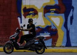 Un motociclista pasa junto a un mural del presidente de Venezuela, Nicolás Maduro, en Caracas el 19 de agosto de 2025.