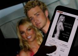 Esta imagen ilustrativa tomada el 21 de octubre de 2023 muestra la portada del libro de Britney Spears The Woman in Me de un minorista en línea frente a una fotografía de Britney Spears y Justin Timberlake en los American Music Awards del 9 de enero de 2002.