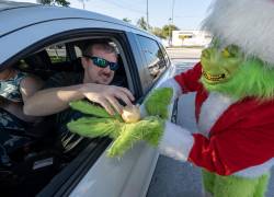 Fotografía cedida por la Oficina de noticias de los Cayos de Florida donde aparece el coronel Lou Caputo, disfrazado de Grinch, mientras entrega una cebolla a un conductor a cambio de una multa.