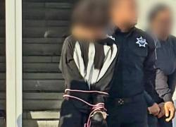 Fotografía que muestra a Omar ‘N’, de 15 años, detenido por un agente de seguridad.