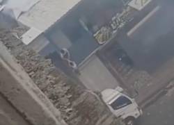 Captura de video en el que se observa a una mujer bajando lentamente a un niño, mientras un hombre espera abajo para atraparlo.