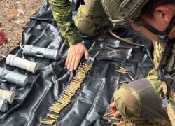 Fotografía que muestra a militares revisando artillería pesada en el campamento.