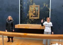 Dos activistas ambientales del colectivo denominado Riposte Alimentaire (Represalias por alimentos) haciendo gestos mientras están parados frente a la pintura Mona Lisa (La Joconde) de Leonardo Da Vinci después de arrojar sopa a la obra de arte, en El museo del Louvre en París.