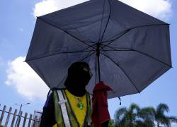 Fotografía que muestra a un ciudadano utilizando una sombrilla para protegerse del sol en Guayaquil.