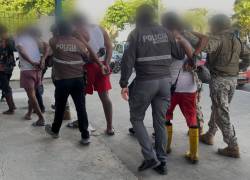 Fotografía que muestra a varios de los detenidos siendo custodiados por uniformados.