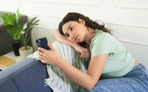 Una adolescente triste mientras usa el teléfono móvil y espera un mensaje o una respuesta de alguien.