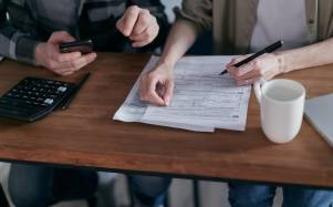 Dos personas hacen cálculos para declarar impuestos.