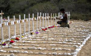 A worker paints graves for unidentified victims of the June 24 earthquake at La Esperanza Cemetery in Catia La Mar, La Guaira state, northeast of Caracas, on July 5, 2026. Venezuela's devastating twin earthquakes killed nearly 3,000, updated official figures showed on July 4, as international rescue teams began winding down search operations for survivors in the rubble of the disaster. (Photo by Miguel MEDINA / AFP)