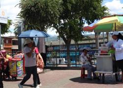 Personas protegiendose del intenso calor solar y radiación ultra violeta con gorras y paraguas.