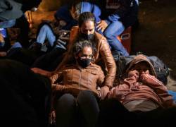 Familias de inmigrantes de Venezuela y Brasil se apiñan para calentarse mientras esperan ser transportados a un centro de procesamiento de la Patrulla Fronteriza de Estados Unidos el 09 de diciembre de 2021 en Yuma, Arizona