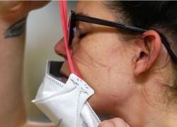 La enfermera Jessalynn Dest se pone una nueva máscara N95 después de salir de la habitación de un paciente con COVID-19 en la unidad de cuidados agudos del Centro Médico Harborview, en Seattle, el viernes 14 de enero de 2022.