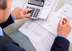 Hombre realizando cuentas con documentos.