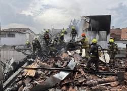 La imagen retrata a bomberos apagando el fuego generado por el fatal choque de una avioneta en el barrio Belén Rosales, ubicado en Medellín, Colombia.