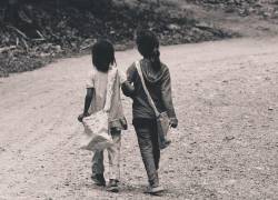 Imagen de referencia en la que dos niñas caminan, tomadas del brazo, por un camino de tierra.
