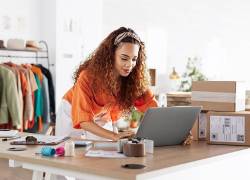 Mujer joven trabajando con inventario de ropa en casa como emprendimiento.