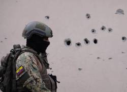 Fotografía de un militar ecuatoriano observando impactos de bala en una pared, en la ciudad de Guayaquil.