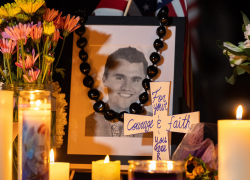 Velas y flores son vistas cercas de un retrato del activista Charlie Kirk en una vigilia en Utah.
