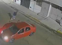 Captura de video que muestra al hombre doblándose de dolor tras recibir un disparo por parte de los asaltantes, quienes se trasladaban en el auto rojo.