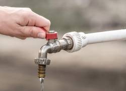 Persona cerrando una llave de agua, en una foto referencial.