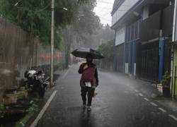 Hombre con paraguas en medio de la lluvia, en una fotografía referencial.