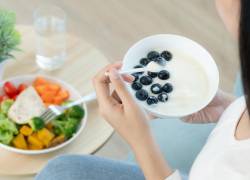 Mujer consumiendo fibra a través de frutas con yogurt griego y vegetales.