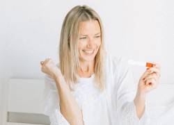 Mujer festejando ante una prueba de embarazo positiva.