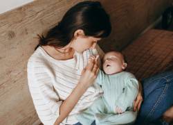 Foto una mamá cargando a su bebé en etapa de lactancia.