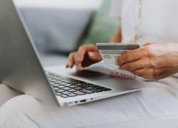 Mujer con tarjeta de crédito digitando en su laptop.