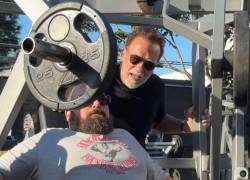 Imagen en la que se ve al fisicoculturista y actor, Arnold Schwarzenegger realizando trabajo de coach de entrenamiento físico.