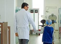 Un niño camina tomado de la mano de un doctor.