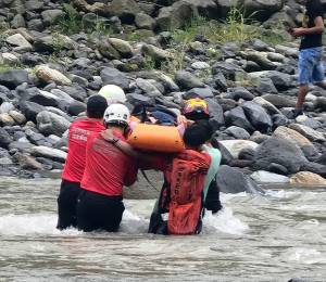 Fotografía que muestra a rescatistas y voluntarios trasladando el cuerpo de la víctima.