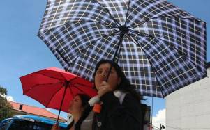 Quiteños se protejan con parasoles de las altas temperaturas durante el día, que se registran en la ciudad capital.
