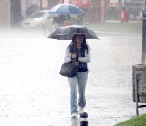 Fotografía referencial que muestra a una mujer en medio de una fuerte lluvia.