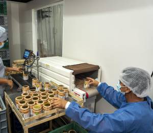 Empleados de la planta de producción de Life Choice etiquetan cremas de maní en sus envases.