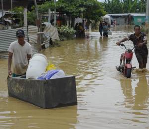 Fotografía que muestra a ciudadanos recuperando sus pertenencias tras una inundación en Balao, Guayas.